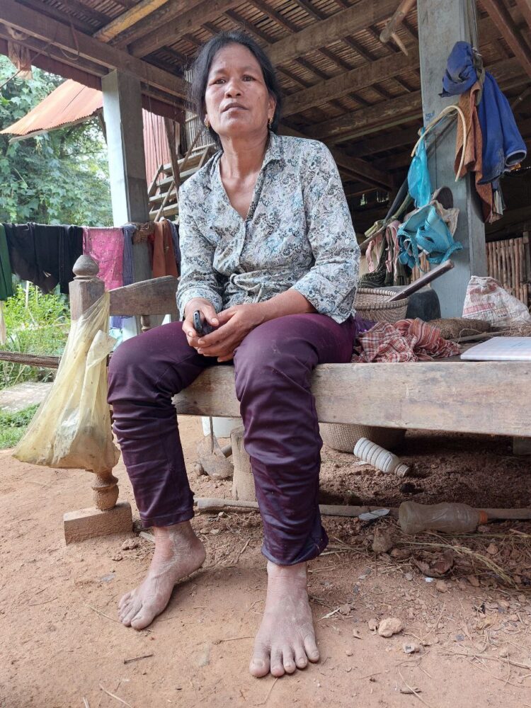 យ៉ី ហឿន ស្ត្រីមេម៉ាយកំពុងអង្គុយលើគ្រែ បន្ទាប់ពីគាត់ត្រឡប់មកពីច្រូតស្រូវ នៅឃុំសំរោង ស្រុកស្វាយអន្ទរ ខេត្តព្រៃវែង។ រូបថតនៅថ្ងៃទី១២ ខែតុលា ឆ្នាំ២០២២។ រូបថតដោយ៖ ម៉ិច ជូឡាយ