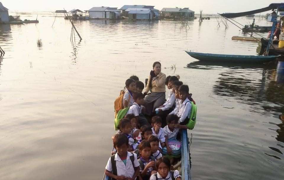 សិស្សានុសិស្សកំពុងជិះទូកជាមួយគ្រូបង្រៀនដើម្បីទៅសាលាបឋមសិក្សាពាក់កន្ទេល ស្ថិតនៅតំបន់បឹងទន្លេសាប ក្នុង ស្រុកឯកភ្នំ ខេត្តបាត់ដំបង។ (រូបភាពផ្ដល់ឱ្យ)