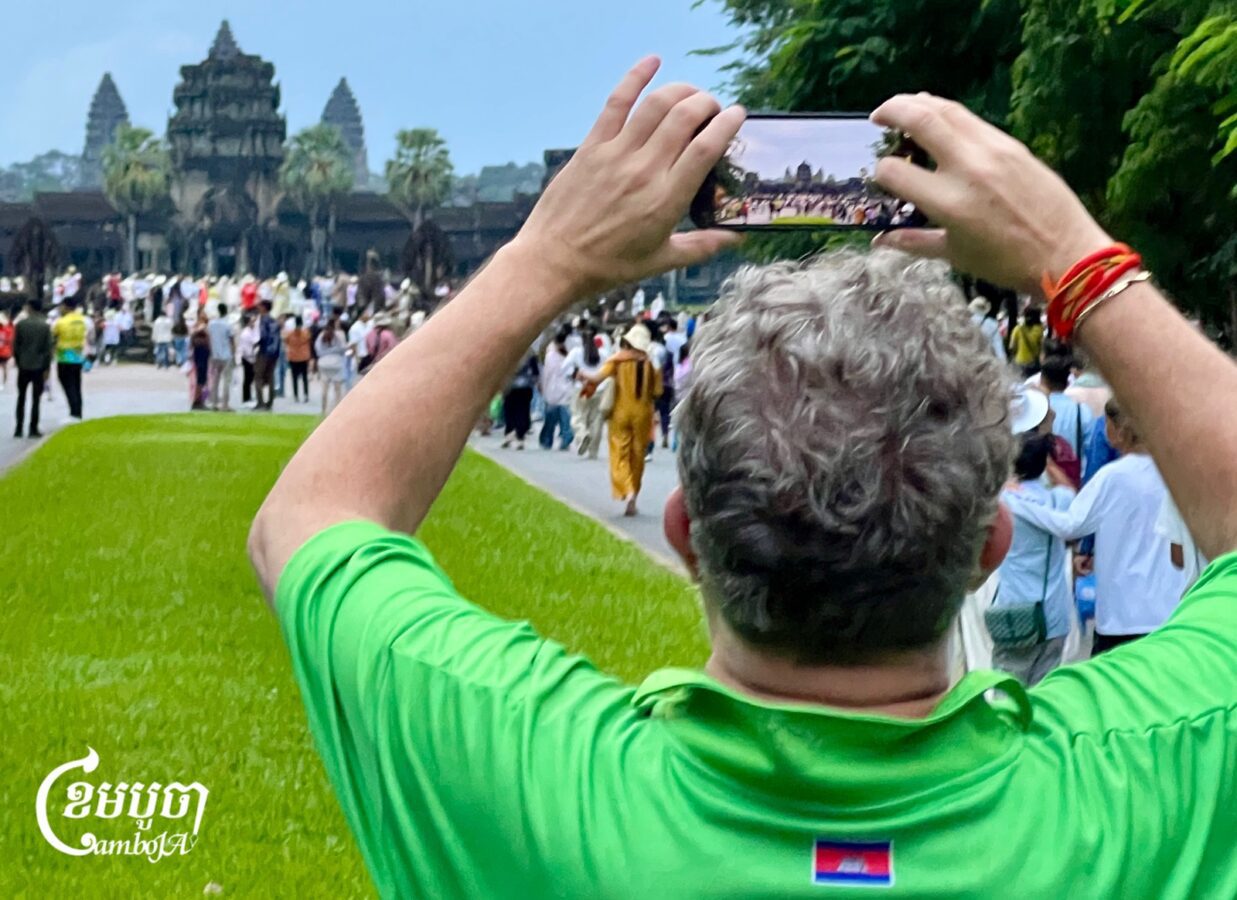 ភ្ញៀវទេសចរបរទេសម្នាក់កំពុងថតរូបប្រាសាទអង្គរវត្ត ភ្ជាប់ជាមួយអ្នកទេសចរជាច្រើនទៀតដែលទៅទស្សនាព្រឹត្តិការណ៍សមរាត្រីនៅថ្ងៃទី២១ ខែកញ្ញា ឆ្នាំ២០២៦។ (ខេមបូចា/ប៉ា តុងចិន)