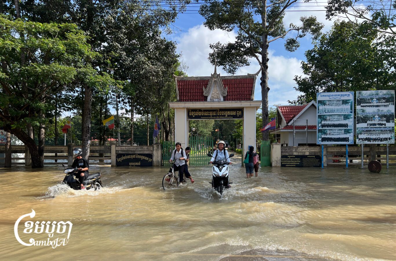 គ្រូ និងសិស្សានុសិស្សធ្វើដំណើរចេញពីវិទ្យាល័យមួយកន្លែងក្នុងស្រុកពួក ខេត្តសៀមរាប ដែលកំពុងរងការជន់លិចដោយជំនន់ទឹកភ្លៀងកាលពីថ្ងៃទី២៨ ខែកញ្ញា ឆ្នាំ២០២៦។ (ខេមបូចា/ប៉ា តុងចិន)